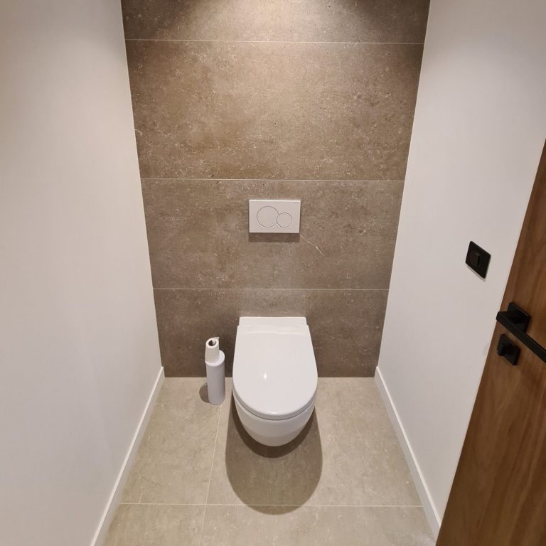 WC suspendu blanc installé devant un mur carrelé